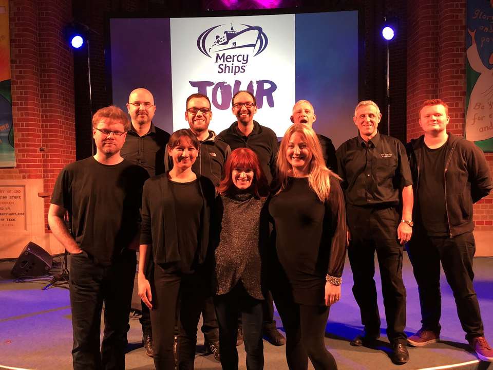 The Top Dog team in front of a Mercy Ships Tour screen